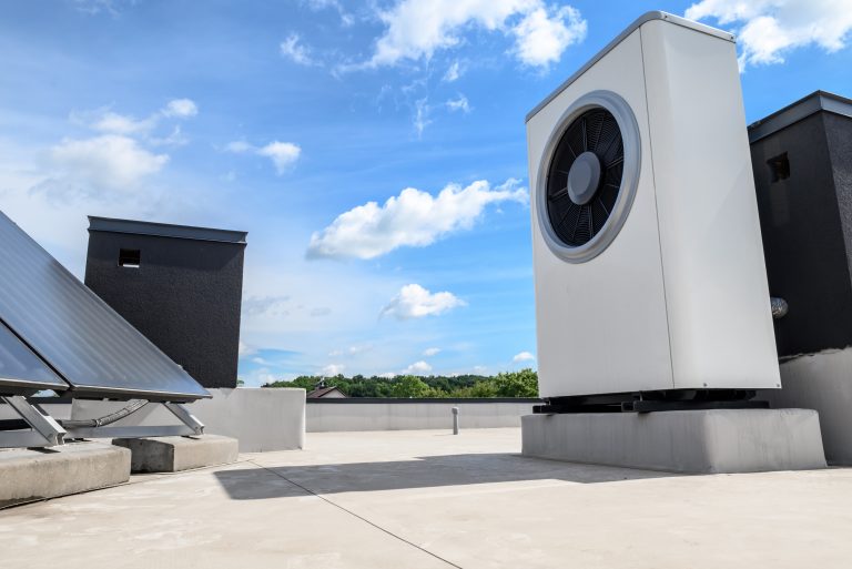 Wärmepumpen-Außeneinheit auf einem Flachdach mit blauer Himmelkulisse