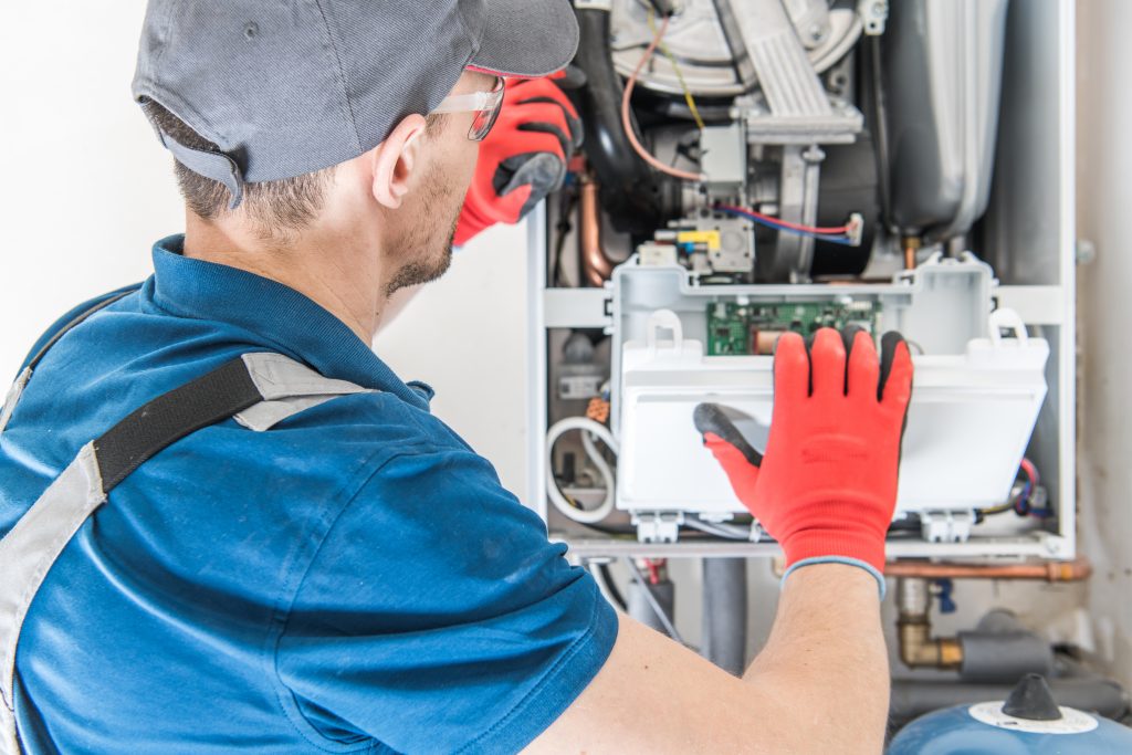 Heizungstechniker wartet eine geöffnete Gastherme in einem Technikraum